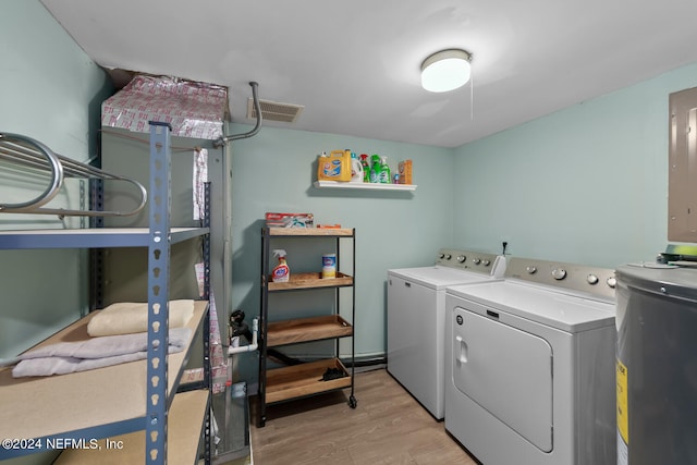 laundry area with light wood-type flooring, washing machine and dryer, and water heater