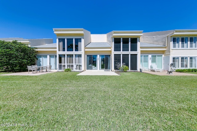 rear view of property with a patio and a lawn