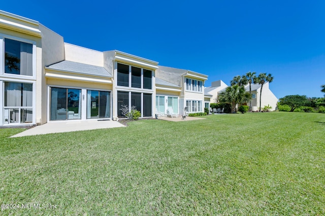 rear view of property with a lawn and a patio