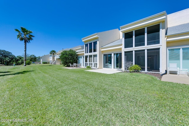 back of property with a yard and a patio