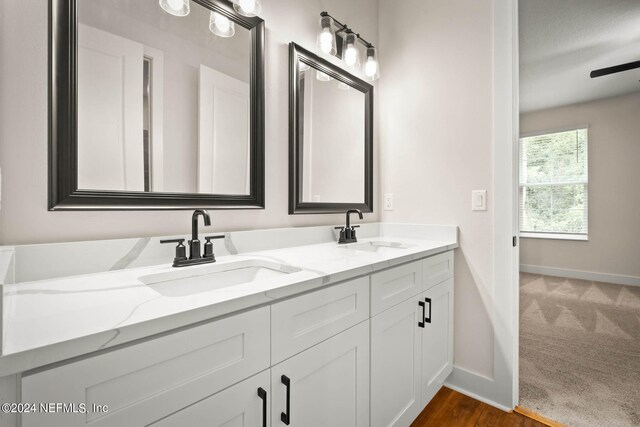 bathroom featuring vanity with extensive cabinet space, wood-type flooring, and double sink