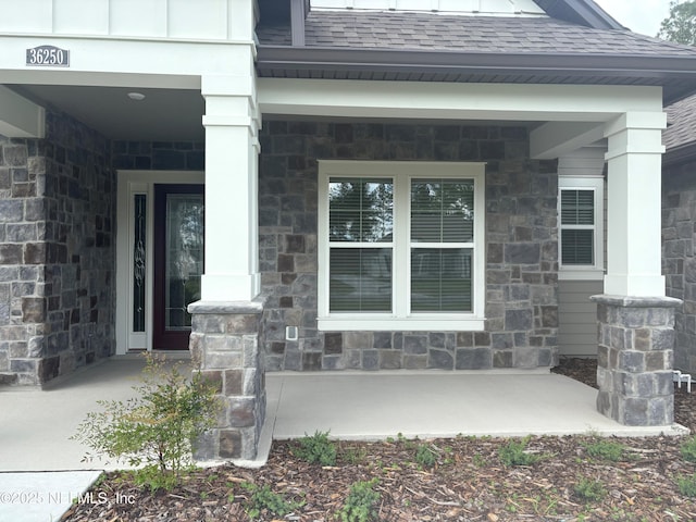 36250 Pitch Ln, Hilliard, FL 32046 - property entrance featuring covered porch, stone siding, and roof with shingles