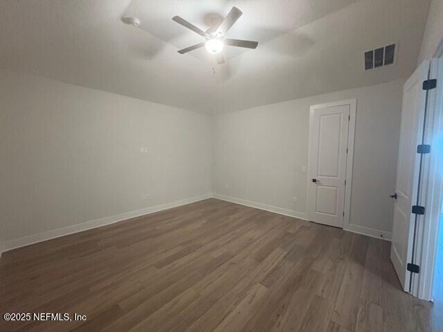unfurnished room featuring baseboards, a ceiling fan, dark wood-type flooring, and visible vents