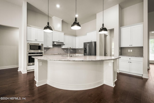 kitchen featuring appliances with stainless steel finishes, backsplash, an island with sink, and dark hardwood / wood-style flooring