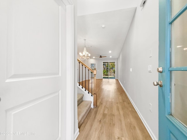 foyer entrance featuring light wood-type flooring and ceiling fan with notable chandelier