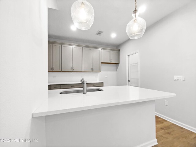 kitchen with sink, hardwood / wood-style floors, pendant lighting, and kitchen peninsula