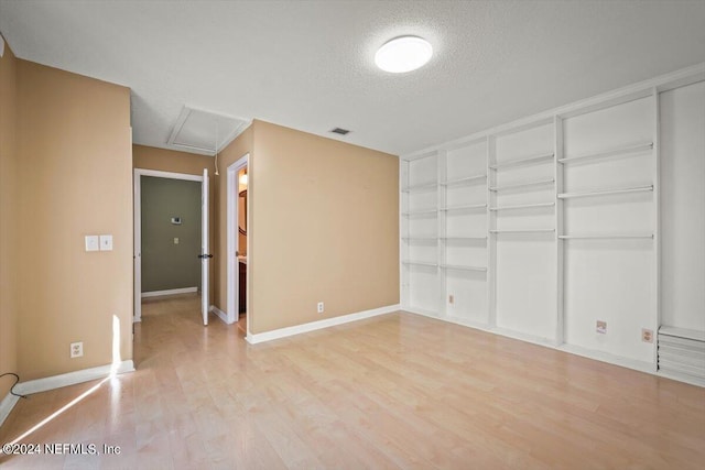 empty room featuring a textured ceiling and light hardwood / wood-style flooring