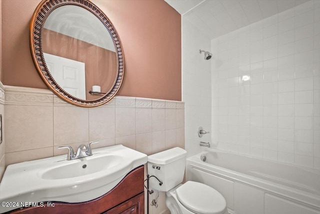 full bathroom featuring tiled shower / bath combo, tile walls, toilet, and vanity