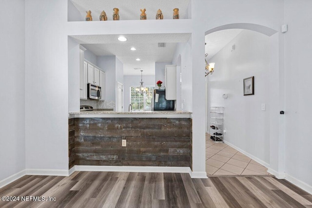 bar with tile flooring, fridge, decorative light fixtures, white cabinets, and a chandelier