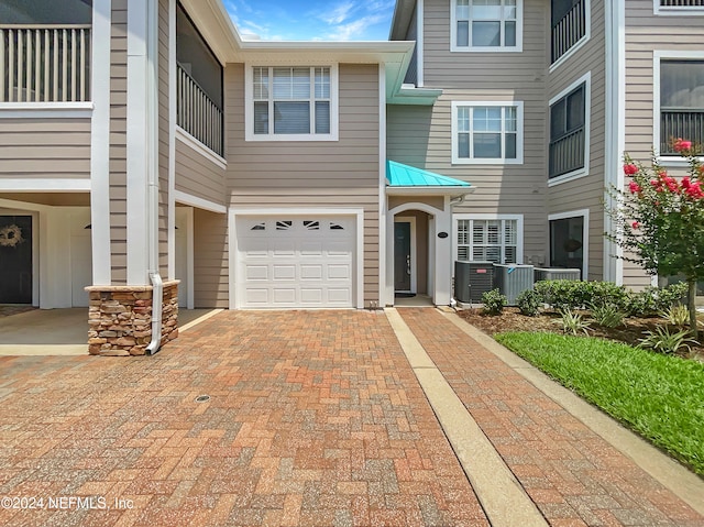 townhome / multi-family property featuring a garage and central AC unit