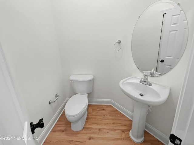 bathroom featuring wood-type flooring, toilet, and sink