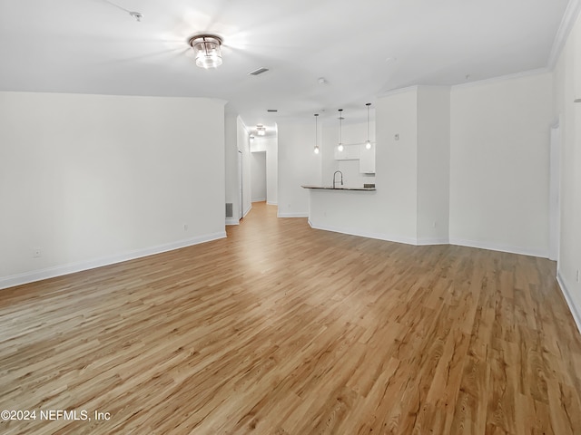 unfurnished living room featuring sink, crown molding, and light hardwood / wood-style flooring