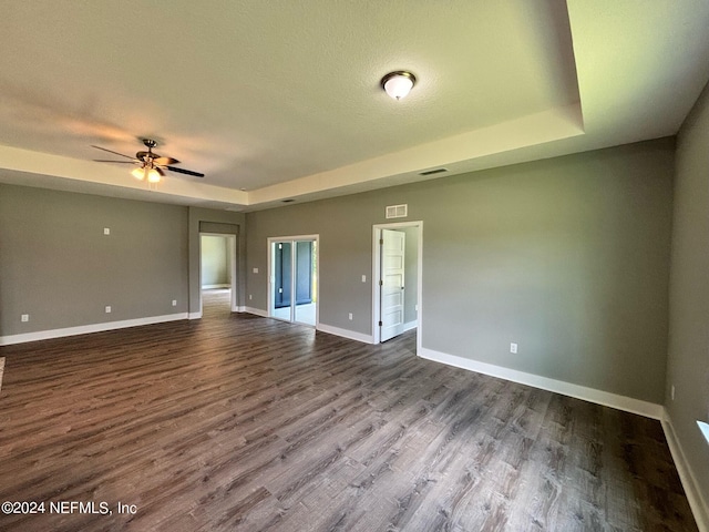 unfurnished room featuring a raised ceiling, ceiling fan, a textured ceiling, and hardwood / wood-style floors