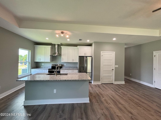 kitchen featuring stainless steel refrigerator with ice dispenser, wall chimney range hood, white cabinetry, sink, and a kitchen island with sink