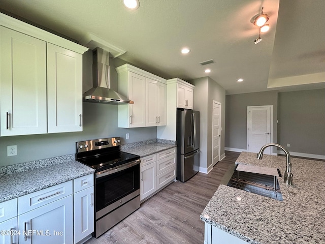 kitchen with white cabinets, wall chimney exhaust hood, sink, and stainless steel appliances