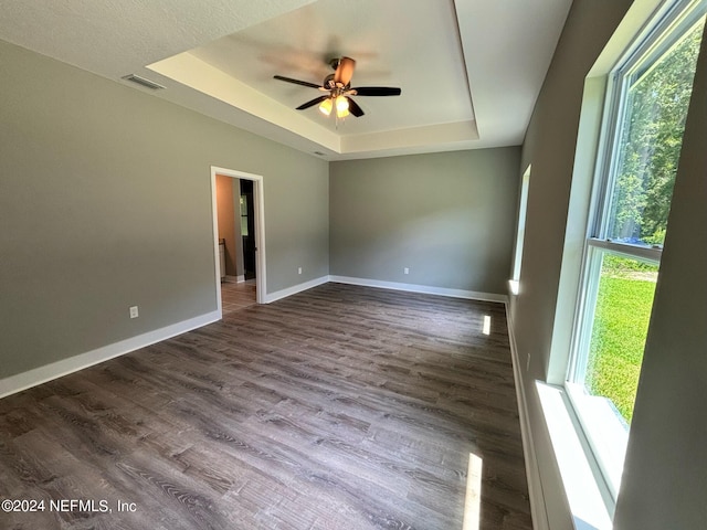 empty room with ceiling fan, wood-type flooring, and a raised ceiling