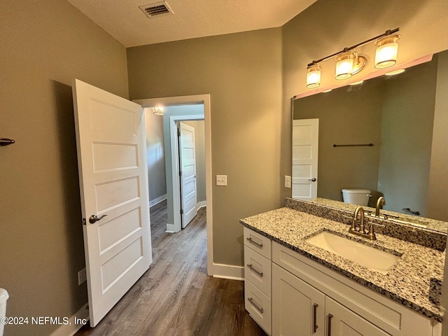 bathroom featuring toilet, vanity, a textured ceiling, and hardwood / wood-style flooring