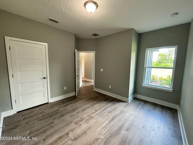 unfurnished bedroom with a textured ceiling and hardwood / wood-style floors