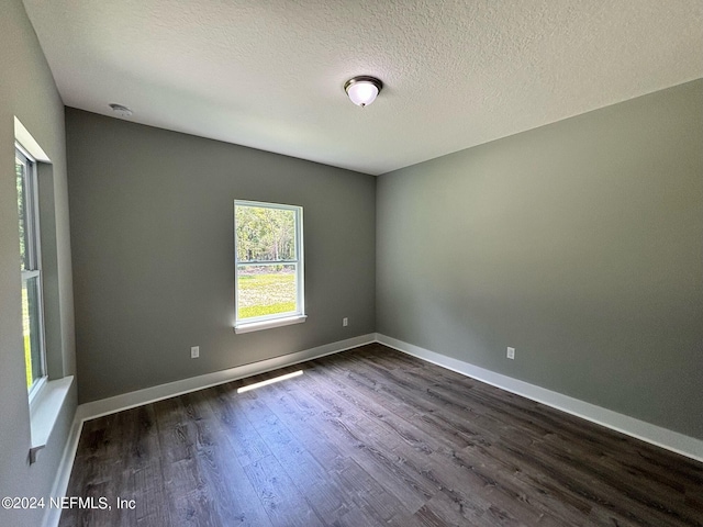 unfurnished room with dark wood-type flooring and a textured ceiling