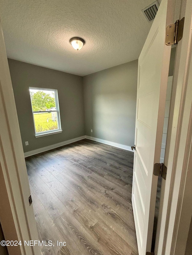 spare room featuring hardwood / wood-style flooring and a textured ceiling