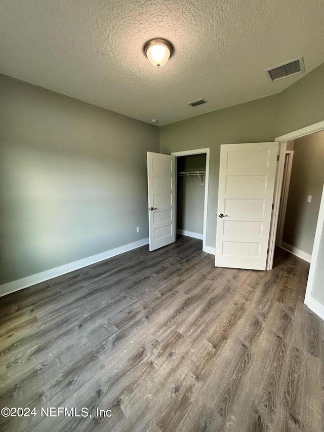 unfurnished bedroom featuring a closet, a textured ceiling, and hardwood / wood-style floors