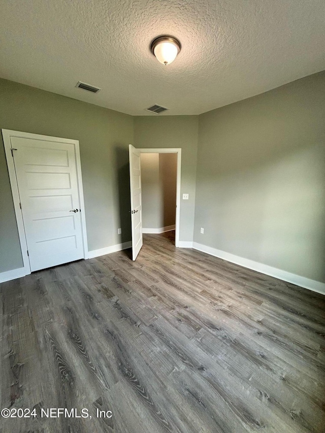 unfurnished bedroom with wood-type flooring and a textured ceiling