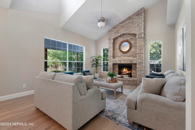 living room featuring a fireplace, light hardwood / wood-style floors, and high vaulted ceiling