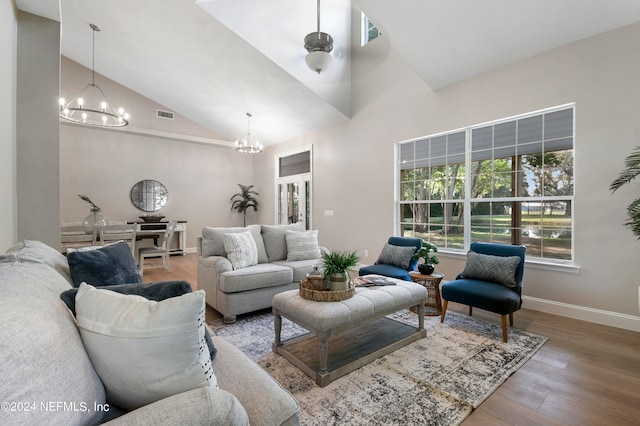 living room with wood-type flooring, high vaulted ceiling, and an inviting chandelier