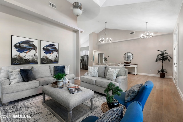 living room with high vaulted ceiling, ceiling fan with notable chandelier, and hardwood / wood-style flooring