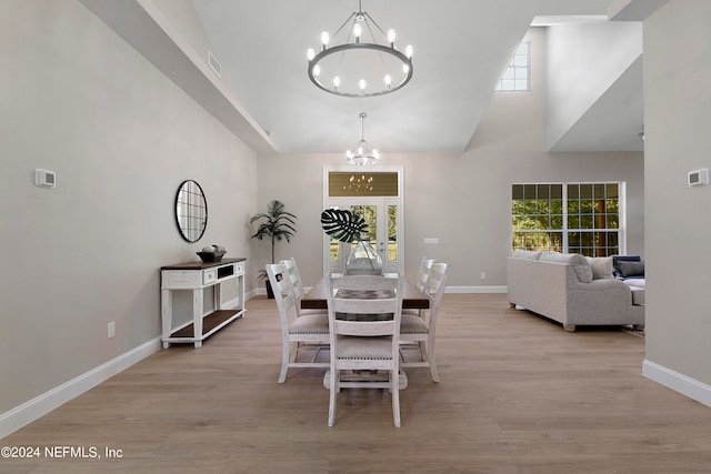 dining space featuring light hardwood / wood-style floors, a high ceiling, and a notable chandelier