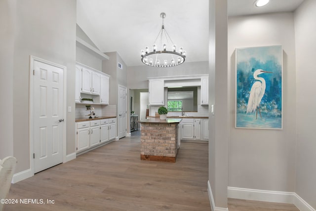 kitchen featuring a notable chandelier, white cabinets, light hardwood / wood-style flooring, tasteful backsplash, and decorative light fixtures