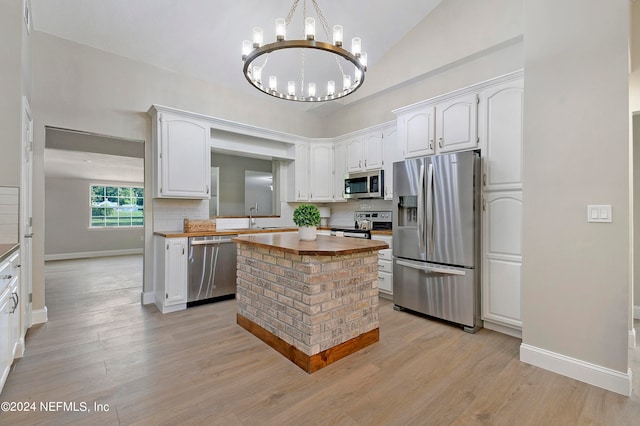 kitchen with vaulted ceiling, white cabinetry, appliances with stainless steel finishes, and wooden counters