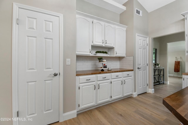 kitchen with butcher block countertops, decorative backsplash, light hardwood / wood-style floors, and white cabinets