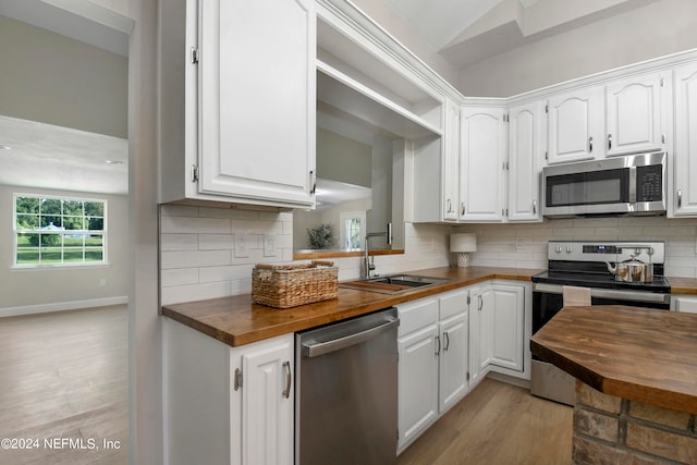 kitchen with sink, stainless steel appliances, tasteful backsplash, wooden counters, and white cabinets