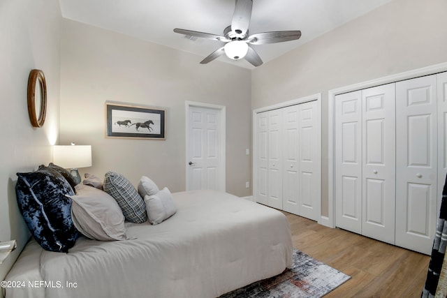 bedroom with ceiling fan, two closets, and light hardwood / wood-style flooring