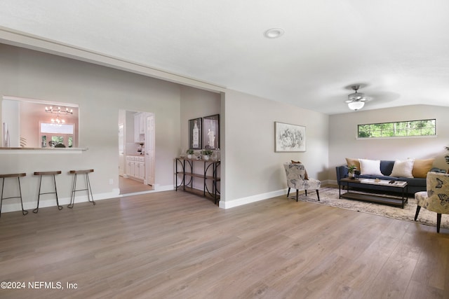 living room featuring ceiling fan, light wood-type flooring, and vaulted ceiling