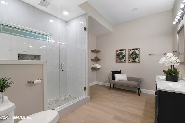 bathroom featuring hardwood / wood-style floors, vanity, a shower with shower door, and toilet