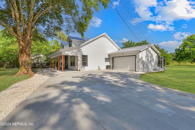 view of front of home with a garage, a front yard, and central AC