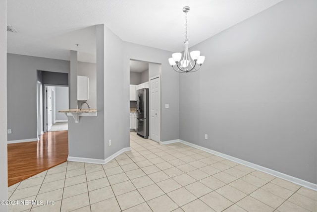 tiled empty room featuring an inviting chandelier