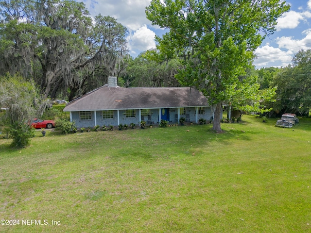 ranch-style house featuring a chimney and a front yard