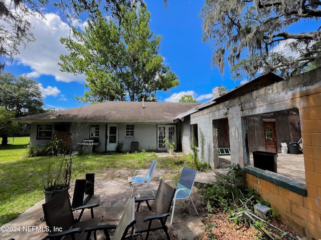 back of property featuring a chimney, a lawn, and a patio area