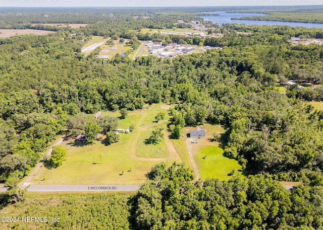 birds eye view of property with a water view and a wooded view