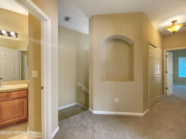 hallway featuring light carpet and sink