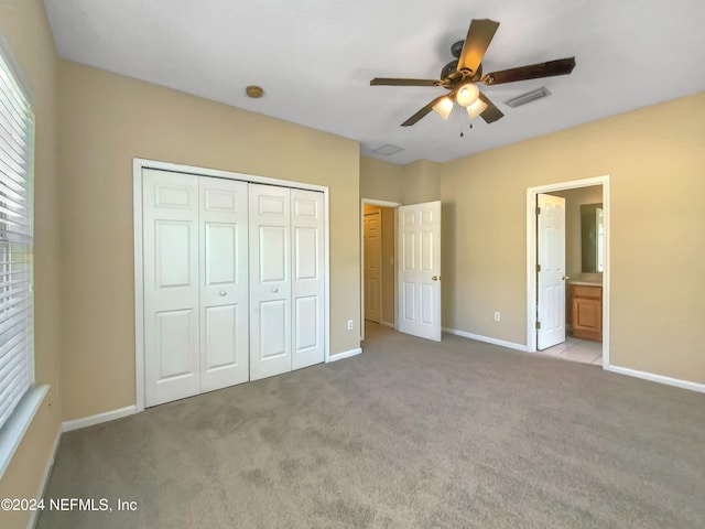 unfurnished bedroom with ceiling fan, ensuite bath, light carpet, and a closet