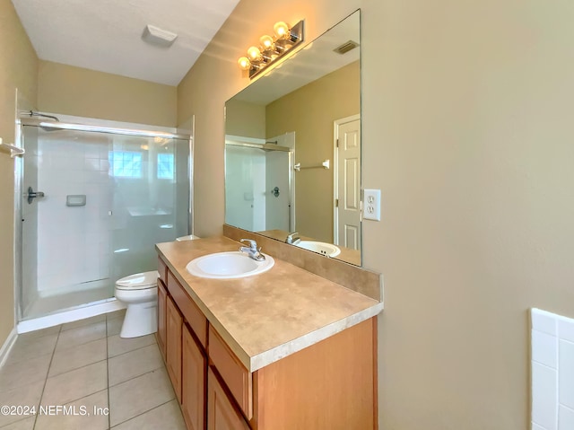 bathroom featuring tile patterned flooring, vanity, toilet, and a shower with shower door