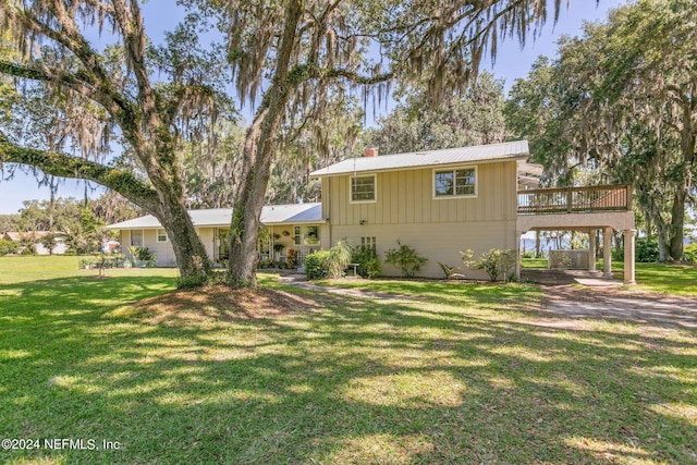 view of front of house with a carport, a wooden deck, and a front lawn