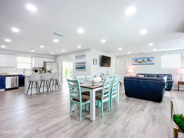 dining area with sink, light wood-type flooring, and a textured ceiling