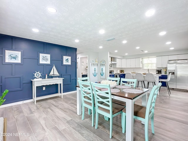 dining area featuring a textured ceiling and light hardwood / wood-style flooring