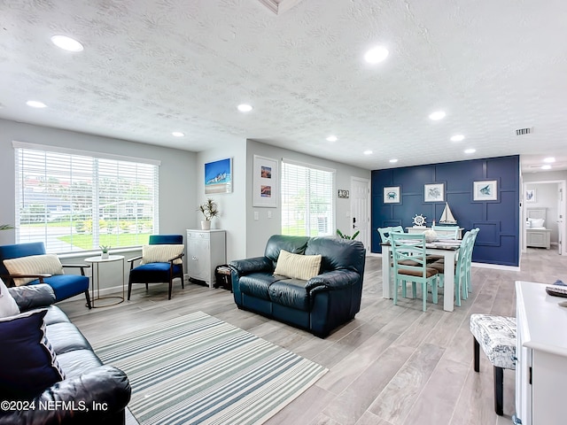 living room featuring plenty of natural light, a textured ceiling, and light hardwood / wood-style flooring