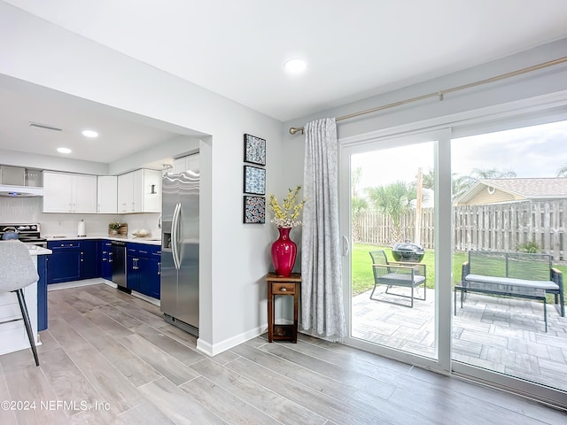 kitchen featuring white cabinets, light hardwood / wood-style floors, blue cabinets, and stainless steel appliances